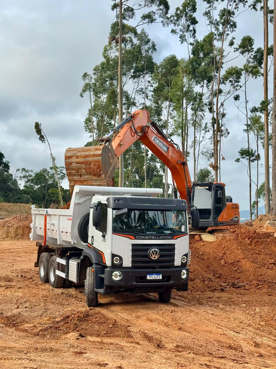 Escavadeira da Trentini carregando caminhão em operação de movimentação de terra